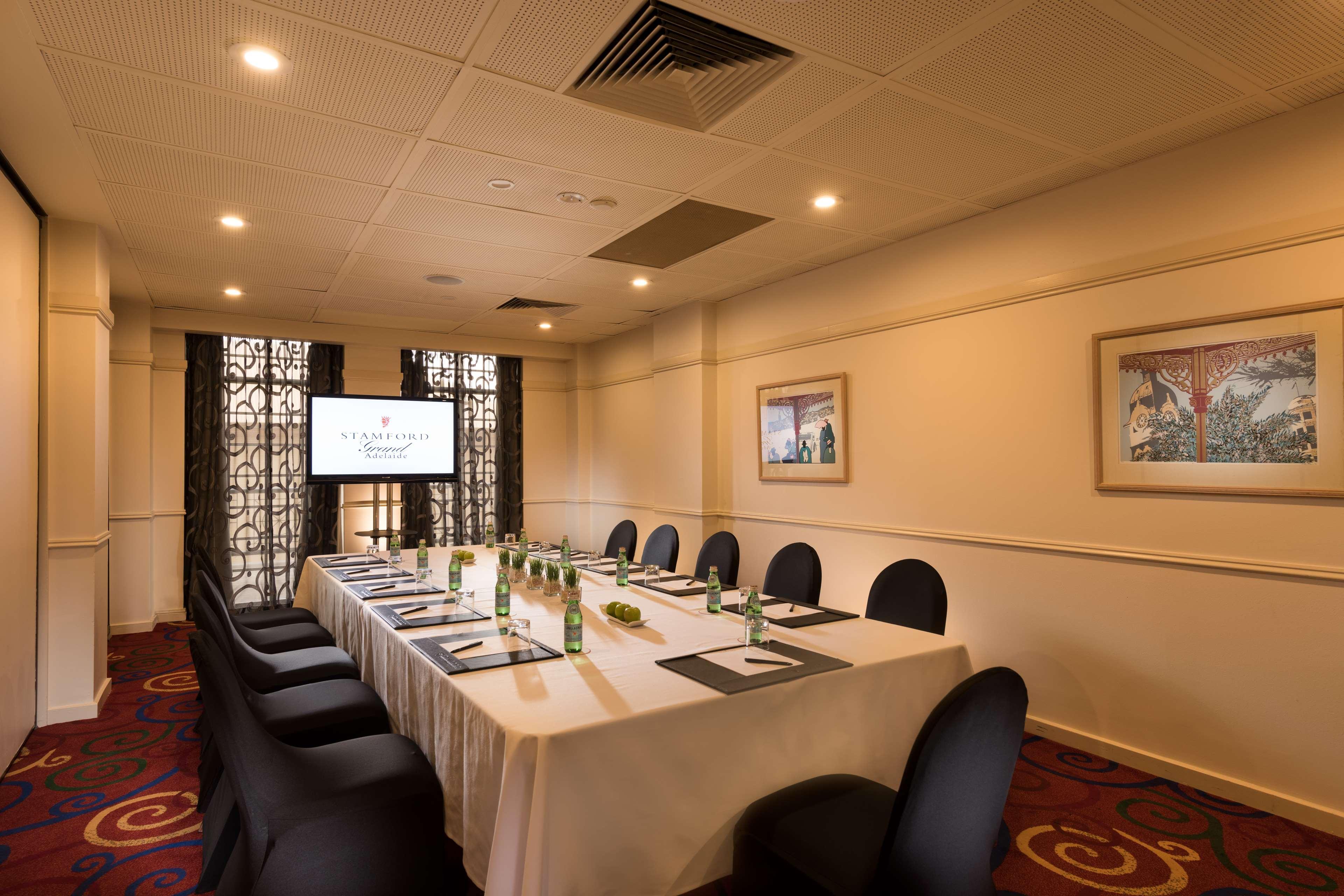 Hotel Stamford Grand Adelaide Glenelg Exterior foto The photo shows a conference room with a long rectangular table set for a meeting. The table is covered with a white tablecloth and has several place settings, including notebooks, pens, and water bottles. There are black chairs around the table, and