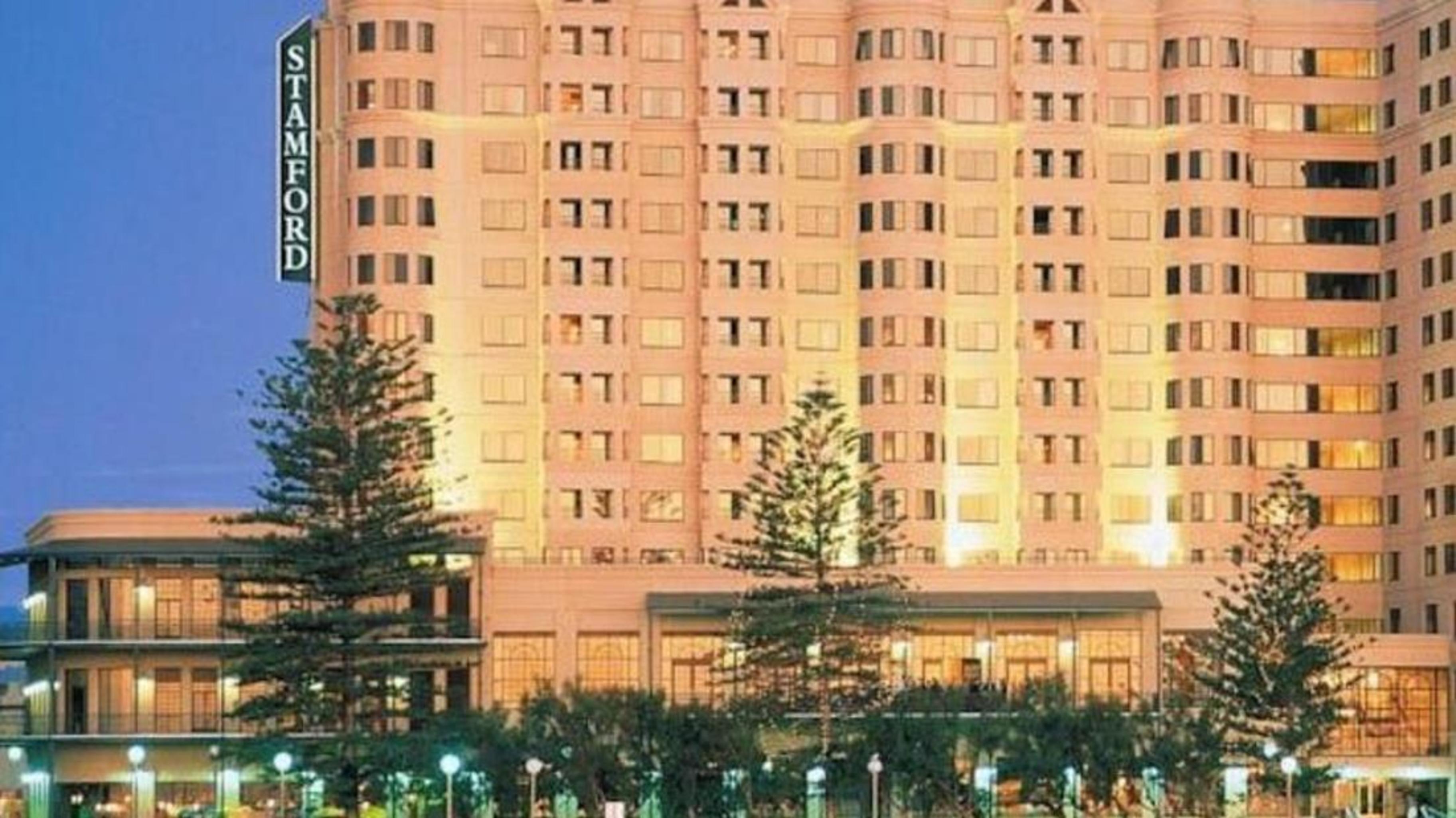 Hotel Stamford Grand Adelaide Glenelg Exterior foto The photo shows a tall, modern building illuminated at night, likely a hotel, with the name "Stamford" prominently displayed on its side. Surrounding the building are several palm trees and landscaped areas, suggesting a tropical or coastal location.