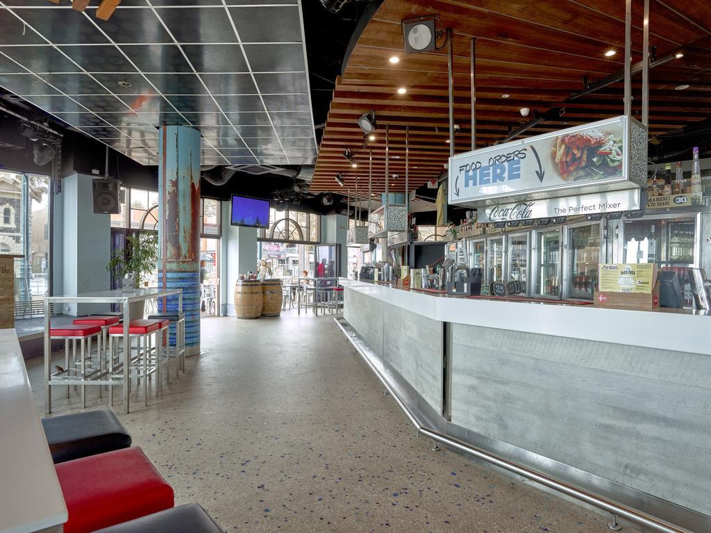 Hotel Stamford Grand Adelaide Glenelg Exterior foto The photo shows the interior of a modern bar or restaurant. The design features a long, white counter that serves as the bar area, with a glass display showing beverages. Behind the bar, there are shelves for drink storage. The space has a mix of sea