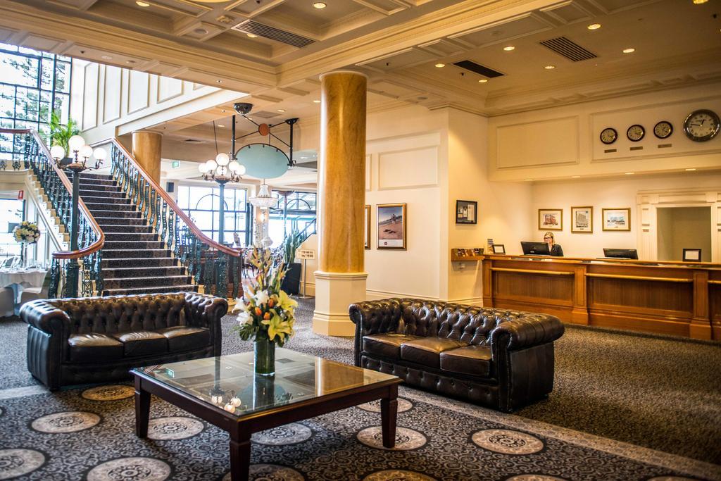 Hotel Stamford Grand Adelaide Glenelg Exterior foto The photo depicts a hotel lobby featuring a spacious and elegant design. There are two dark leather sofas arranged in front of a glass coffee table, adorned with a floral centerpiece. The lobby has a refined atmosphere, highlighted by large windows t