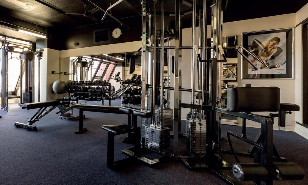 Hotel Stamford Grand Adelaide Glenelg Exterior foto The photo shows a gym interior with several pieces of exercise equipment. In the foreground, there is a multi-station machine that features various pulleys and weights. To the side, there are benches and free weights, including dumbbells. The gym has